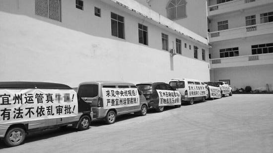今年7月，宜州市運(yùn)管局通過了當(dāng)?shù)亓硪患臆嚈z企業(yè)開展?fàn)I運(yùn)車輛綜檢業(yè)務(wù)的備案，引發(fā)原來“獨(dú)家壟斷”河池綜檢市場(chǎng)的企業(yè)的不滿，其員工打出各種抗議標(biāo)語。 資料圖片